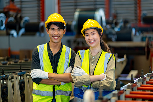 Portrait of smiling Asian technician engineer workers team inside the manufacturing factory line production