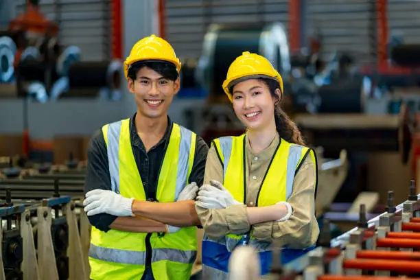 Photo of Portrait of smiling young Asian technician engineer workers team inside the manufacturing factory line production