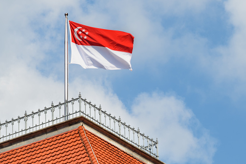 The Flag of Singapore fluttering on blue sky background. Singapore is a popular tourist destination of Asia.