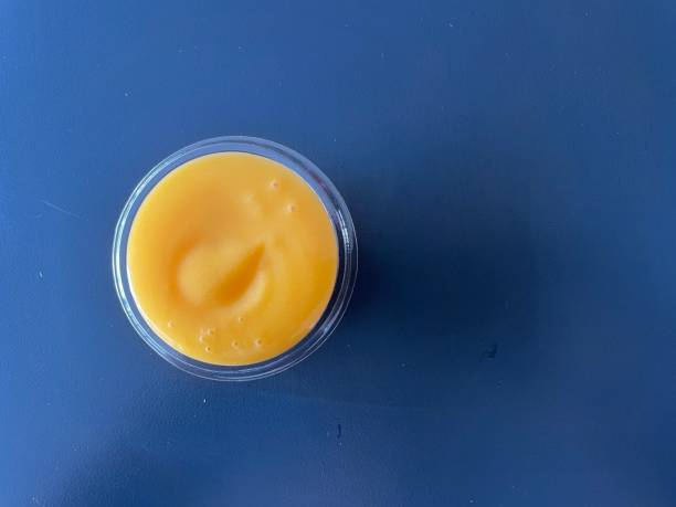 melted cheese on a small transparent plastic plate on a dark blue background melted cheese on a small transparent plastic plate on a dark blue background cheese sauce stock pictures, royalty-free photos & images