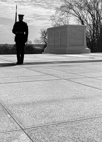 Black & white image of soldier guarding the tomb of the unknown soldier at Arlington National Cemetery.