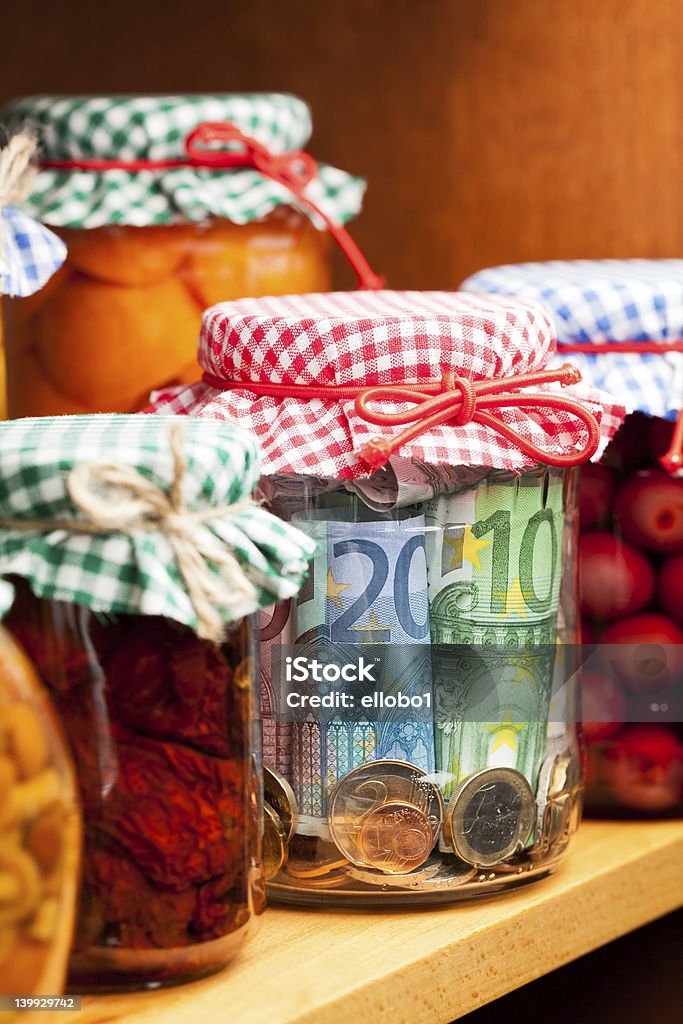 Jars of preserved fruits and money Money conserved in a glass jar among others preserves. European Union Currency Stock Photo