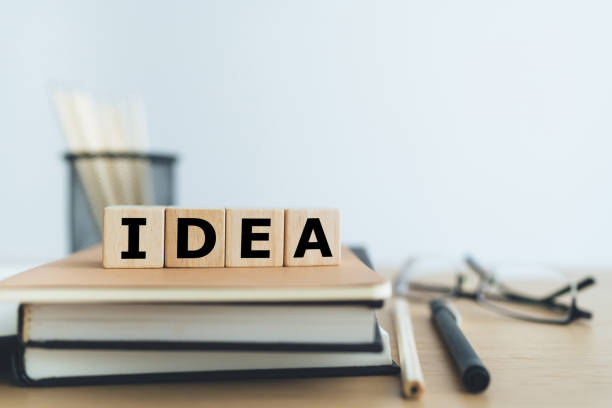 istock Wooden cube with IDEA with book or textbook. Business working or education learning success idea. Businessperson or student knowledge, creativity and skill improvement. 1399297439