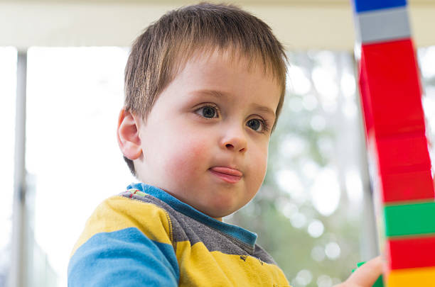 Young boy concentrates while building a tower stock photo