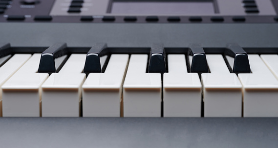 Electronic piano keys close up view on blurred buttons and screen  background