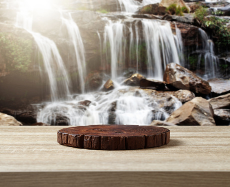 Wooden cuttingboard on wooden table for standing product against nature landscape