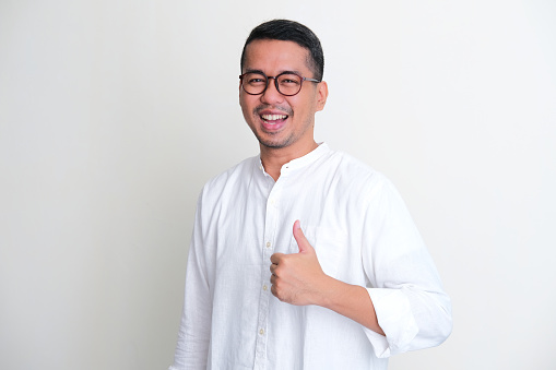 Adult Asian man smiling proud while giving thumb up
