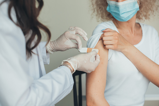 Doctor stick Medicinal plaster on woman arm after being vaccinate. oronavirus pandemic protection concept. Healthcare concept. Corona virus immunization, protection, medicine treatment concept.