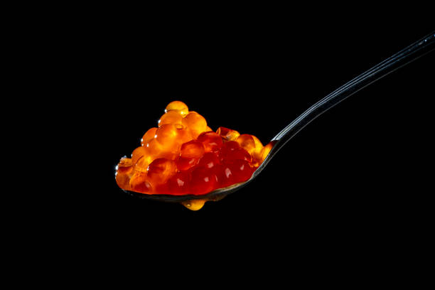 Fresh red caviar in a spoon on a black background