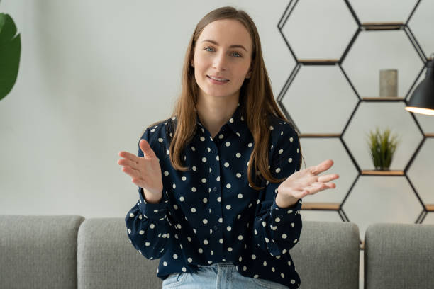 istock Young happy Caucasian woman speaks while looking at the camera while sitting on the sofa in the living room of the house. A woman working at an online web conference 1399320113