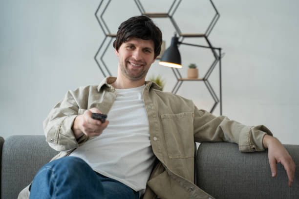 istock Young man holding television remote control smiling and laughing hard out loud 1399320156