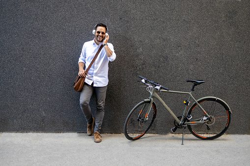 Business man in the city standing against black wall next to his bike