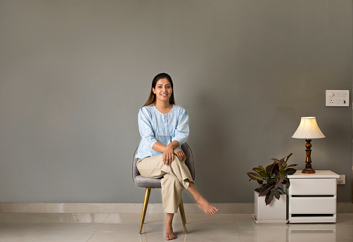 Smiling young woman sitting on chair at modern home