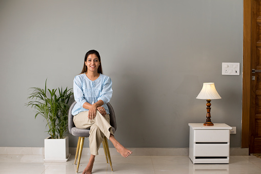 Smiling young woman sitting on chair at modern home