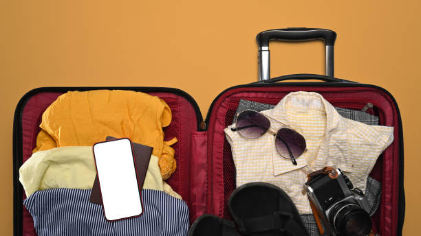 istock Open suitcase, smart phone, sunglasses, camera and passport on yellow background for summer holidays. Top view. 1399322686