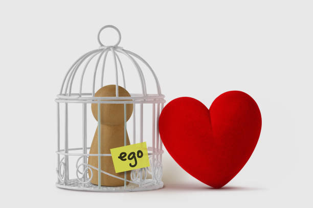 Pawn in a bird cage with the word Ego written on paper note and free heart  - Love and ego concept stock photo