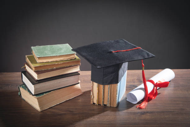 istock Graduation hat, book and diploma on the wooden table. 1399334529