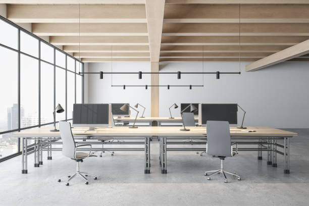 istock Front view on minimalistic design work places with modern computers on wooden tables, grey stylish chairs in spacious coworking office with wooden ceiling and concrete floor. 3D rendering 1399334704