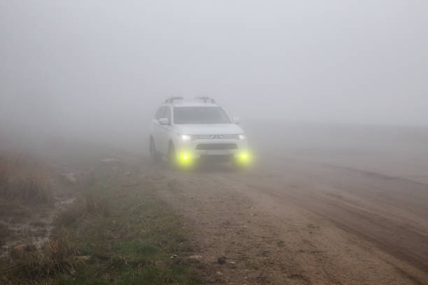 Gum-Bashi pass, North Caucasus, Russia - May 07, 2022: Crossover SUV Mitsubishi Outlander on a mountain road in thick fog with fog lights