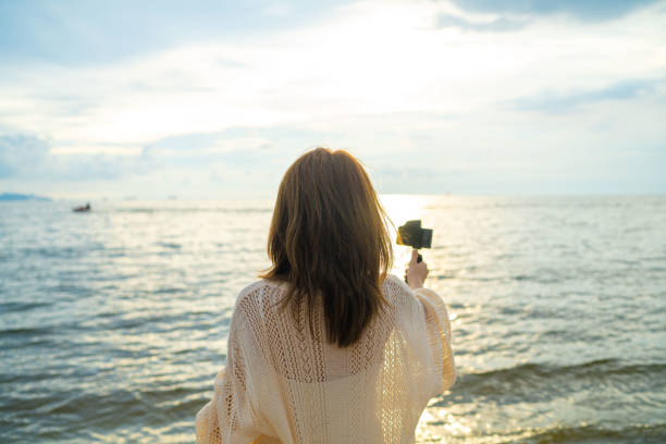 istock Asian influencer recording vlog while sunset at beach. 1399337374