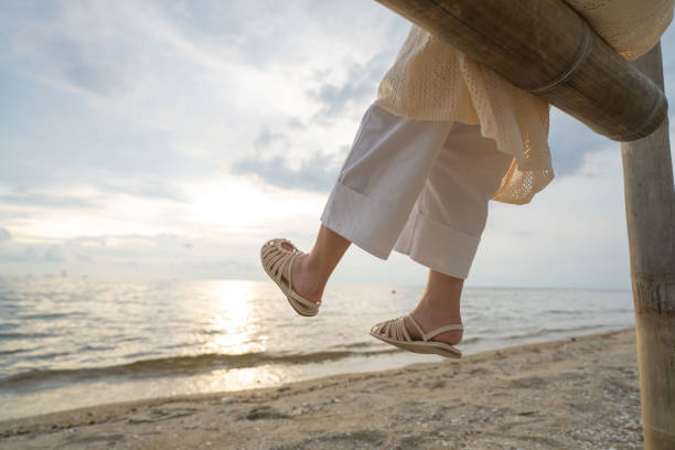 Beautiful Asian woman enjoying sea view on swing by the sea in summer time.