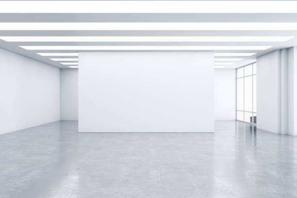 istock Empty spacious light exhibition or gallery hall with front view on blank white wall, glossy concrete floor, white ceiling and windows. 3D rendering, mockup 1399337646