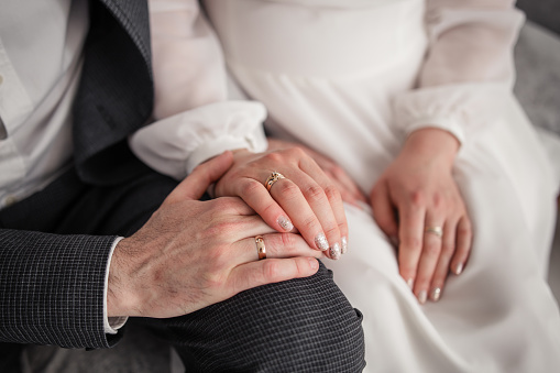 a woman's hand on a chair with a golden ring at the bride