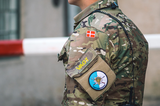 Copenhagen, Denmark - May 23 2022: Flag of Denmark and Emblem for the Danish Royal Life Guards on a soldier uniform. Danish Army, member of NATO force integration unit, close up