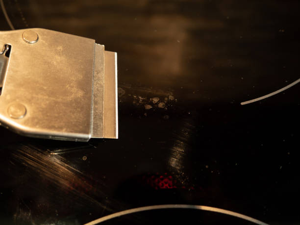 istock Built-in induction or electric hob with ceramic surface. A man uses a scraper to clean an induction cooker. Dirty surface. Cooking plate. 1399339195