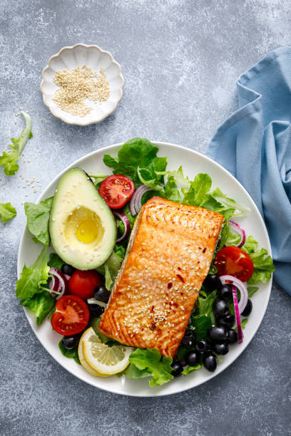 Grilled salmon fish fillet and fresh vegetable salad with tomato, red onion, black olives and avocado Grilled salmon fish fillet and fresh vegetable salad with tomato, red onion, black olives and avocado mediterranean food stock pictures, royalty-free photos & images