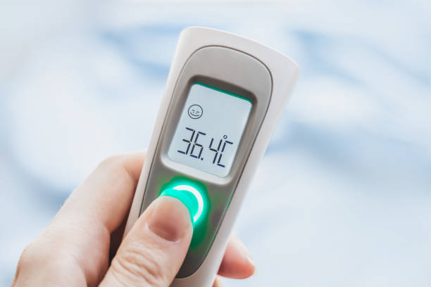 hand holding ir thermometer with normal temperature. close up. infrared temperature measuring device. healthcare home action. non-contact thermometer - infrared thermometer imagens e fotografias de stock