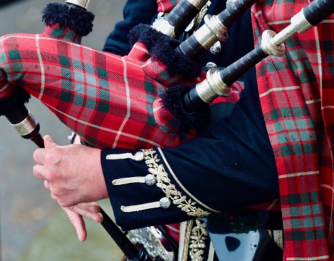 Scottish highlander wearing kilt and playing bagpipes