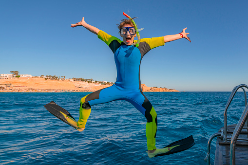 Funny comical snorkeling diver with flippers jump in sea water