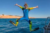Funny comical snorkeling diver with flippers jump in sea water