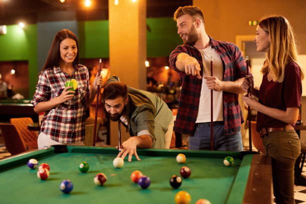 istock Group of friends having fun while playing pool in a local pool hall 1399345217