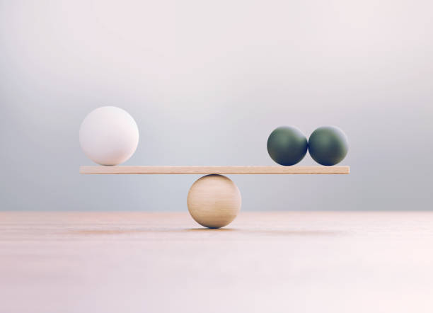 White And Black Wooden Blocks Sitting Over Wooden Seesaw Scale Before Defocused Background Black and white wooden blocks sitting over wooden seesaw scale before defocused background. comparison stock pictures, royalty-free photos & images