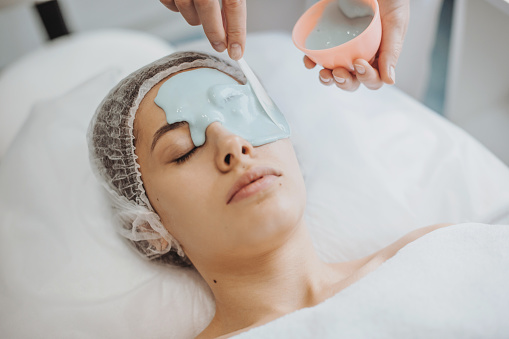 Beautician's hands applying alginate mask on the face of a caucasian woman in a spa salon. Facial skin treatment. Beauty skin. Facial skincare.