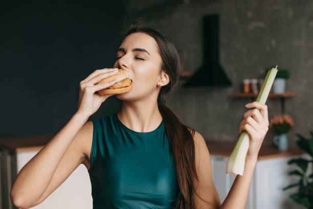 donna sportiva affamata che sceglie di mangiare un hamburger e non vuole scegliere la verdura. cibo non nutriente vs sano. concetto di scelta. cibo sano, dieta. - 4767 foto e immagini stock