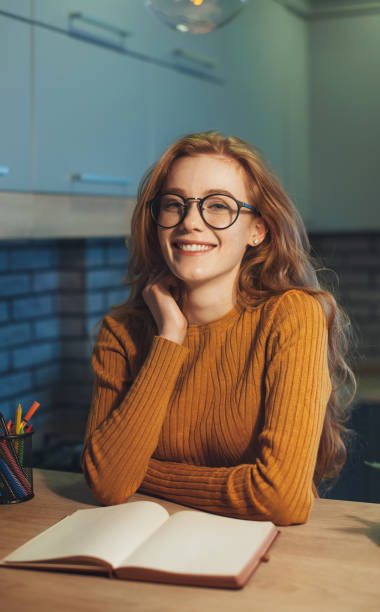istock Happy student girl taking break sitting at table looking and smiling at camera while read paper book. Beauty face. Business portrait. 1399346691