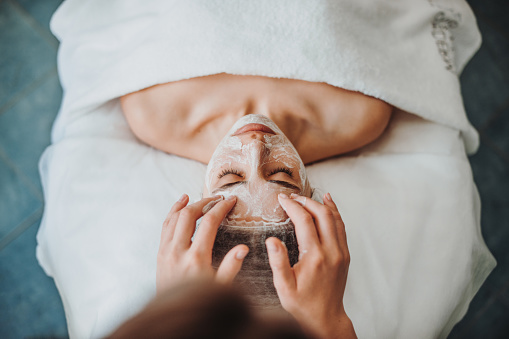 Woman getting facial care by beautician's hands at spa salon. Beautiful girl. Beauty face. Natural beauty. Cosmetology beauty procedure. Facial skin treatment. Rejuvenation treatment.