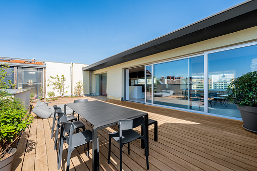 Hardwood rooftop patio deck with a picknick table and chairs. There is also a rooftop garden with plants. Floor to ceiling sliding doors open up to the loft apartment.
