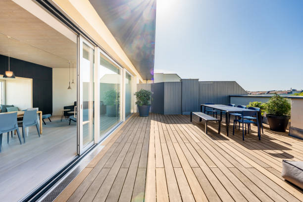 Luxury Rooftop Deck Patio Hardwood rooftop patio deck with a picknick table and chairs. Floor to ceiling sliding doors open up to the loft apartment. apartment balcony garden stock pictures, royalty-free photos & images