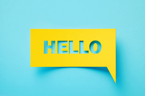 Hello written rectangular shaped yellow chat bubble sitting on turquoise background. Horizontal composition with copy space.