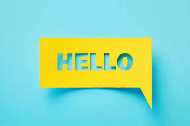 Hello written rectangular shaped yellow chat bubble sitting on turquoise background. Horizontal composition with copy space.