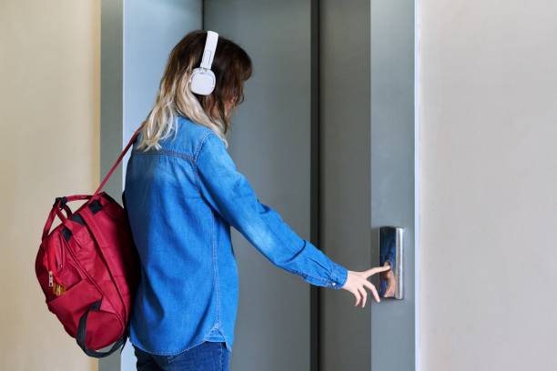 istock Female with backpack standing near elevator door pressing call button 1399349358