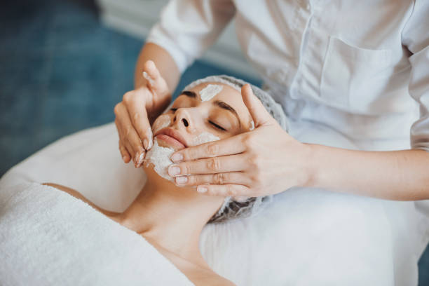Beautiful woman receiving facial massage and spa treatment at beauty salon. Cosmetology beauty procedure. Facial skincare. Facial treatment. Young woman skin care. Beauty face. stock photo