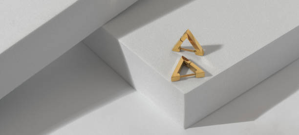 istock Panoramic shot of triangle golden earrings on geometric white background 1399351116