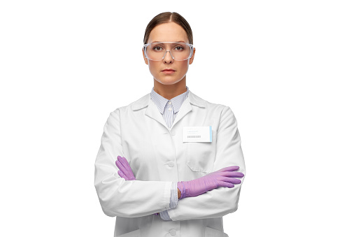 science and profession concept - female scientist in goggles and gloves with nametag on lab coat