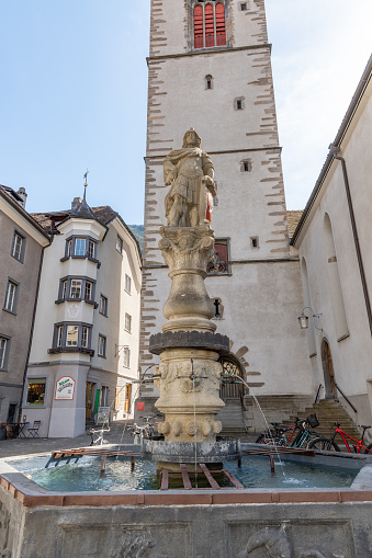 Chur, Switzerland, April 11, 2022 Historic saint Martins water fountain in the old town on a sunny day