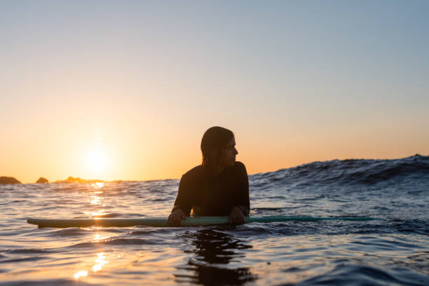 istock Surfer girl waiting for a wave in the water at sunset 1399352995